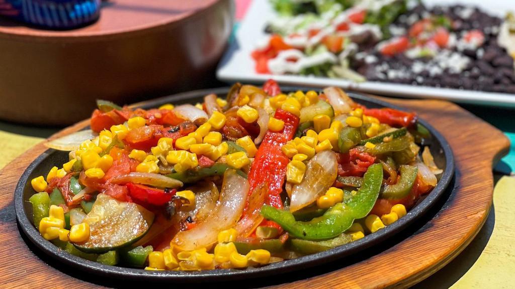 Veggie Fajitas · Red and green bell peppers, onions, tomatoes, zucchini, and corn. Served with a side of white rice vegetable medley, black beans topped with fresh lime pico de gallo, and a side salad (lettuce, tomato, sour cream, and queso fresco) and a side of flour tortillas.