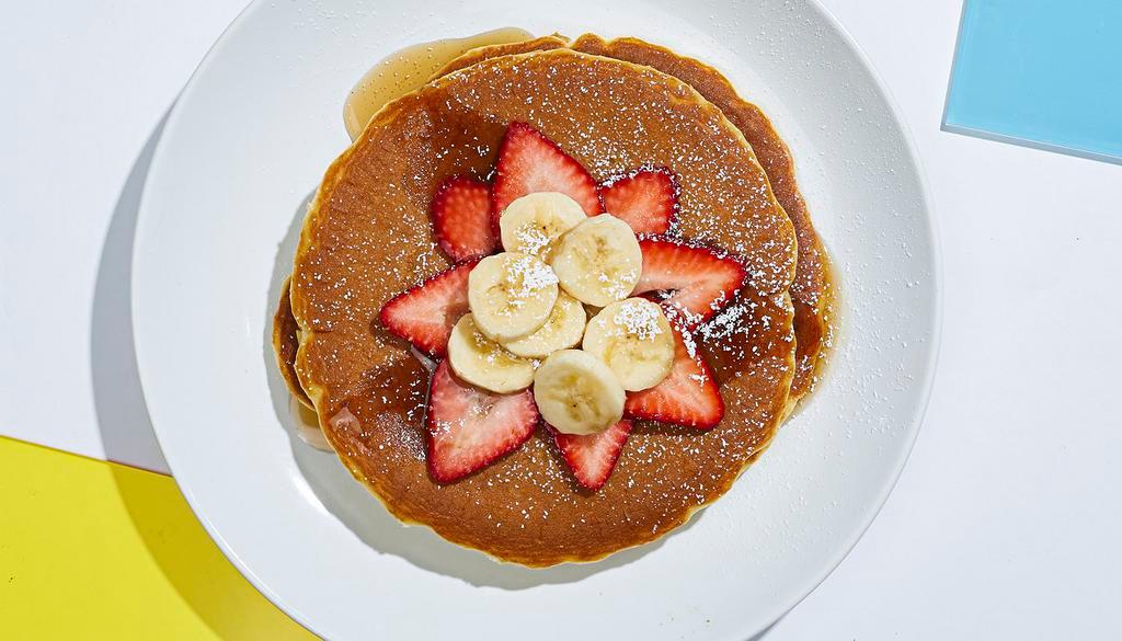 Vegan Berry Pancakes · Two buckwheat pancakes with bananas, blueberries, strawberries, maple syrup and powdered sugar.