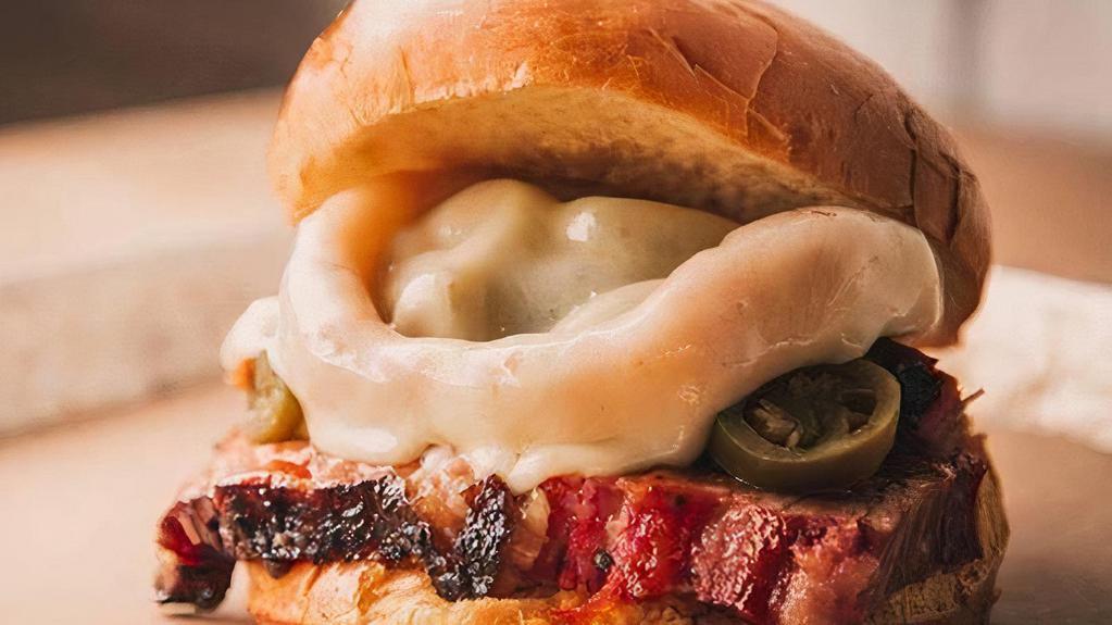 Texas Destroyer · Signature Angus Brisket topped with onion rings, jalapeños, melted provelone cheese, served on a brioche bun and smothered in 4R Signature Sauce.