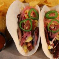 2 Smoked Brisket Tacos · Pickled red onion, onion cilantro, Cotija cheese, cowboy sauce & fresh jalapeños. Served wit...