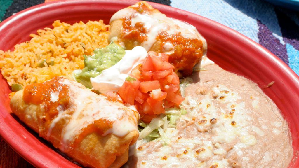 Chimichanga · Two deep-fried chimichangas, one filled with shredded chicken and one filled with shredded beef topped with chile con queso and ranchero sauce.