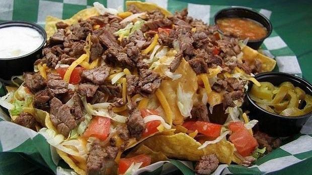 Whole Lotta Steak Nachos · Crispy tortilla chips smothered with queso and topped with cheddar jack cheese, lettuce, tomato and grilled Angus skirt steak. Sour cream, signature salsa and sliced jalapeños served on the side. (1350 Cal)