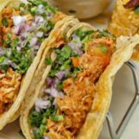 Tacos De Tinga · Shredded chicken tacos seasoned with adobo chipotle, topped with raw red onions, cilantro an...