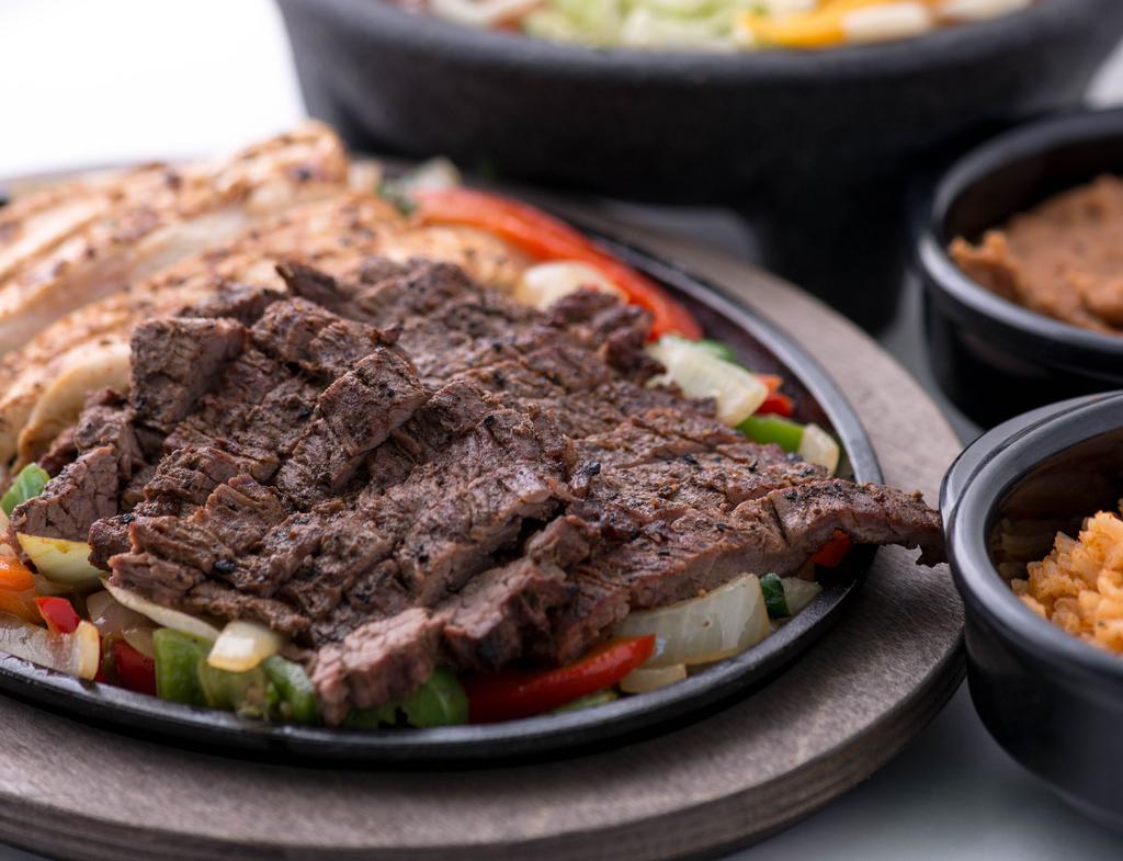 Combo Fajitas · A combination of beef and chicken marinated in our signature blend of Shiner Bock® beer, serrano peppers, lime juice and secret spices.  Grilled with onions and peppers. Served with lettuce, guacamole, sour cream, cheese, tomato, flour tortillas, Mexican rice and refried beans.