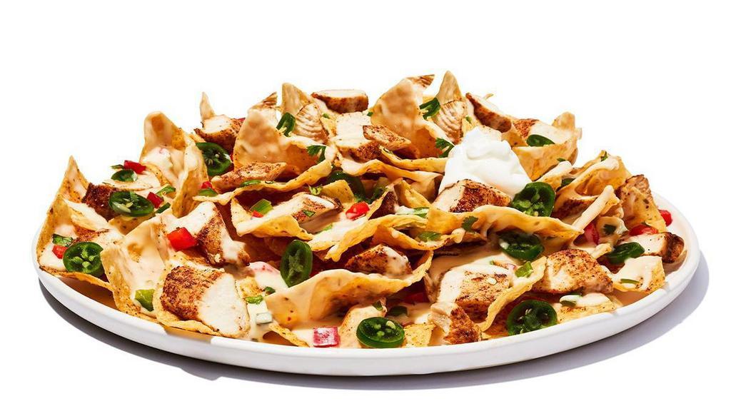 Tex-Mex Nachos Chicken · Fresh-made corn chips loaded with cheese and chili, piled high with diced tomatoes, jalapenos and sour cream.