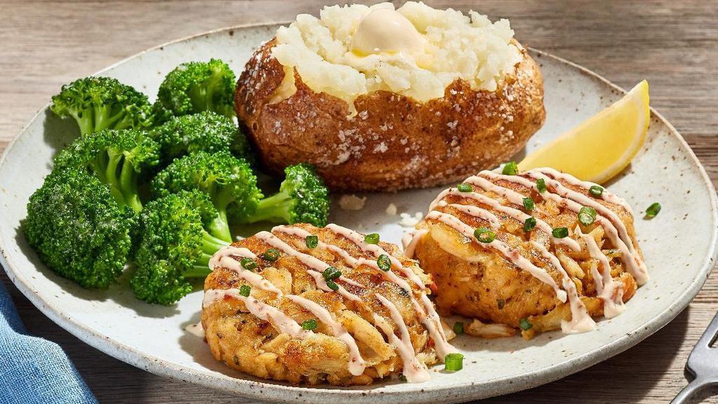 The Crab Cake Dinner* · Two pan-seared lump crabmeat cakes drizzled with our tangy lemon sauce, topped with sliced green onion. Served with choice of two sides.