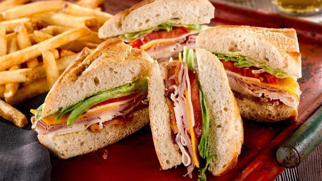 The Club Sandwich · Turkey, bacon, ham, cheddar and Monterey Jack cheeses with lettuce, tomato and mayo. Served with fries.