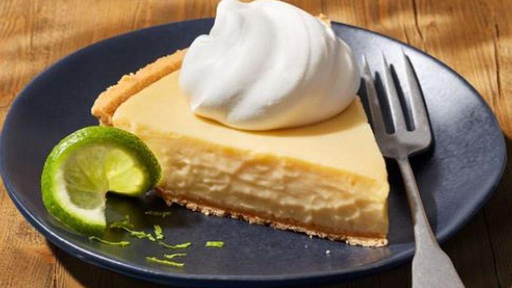 Key Lime Pie - Slice · Tangy, creamy, smooth and the perfect ending to a great meal. This pie comes in a graham cracker crust topped with whipped cream.