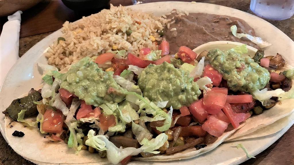 Vegan Tacos Al Carbon · Vegetarian. Veggie blend of green peppers, red peppers, onions, mushrooms, tomatoes, peas, corn and black beans charred on the grill. Served into three corn tortillas. Topped with lettuce, pico de gallo, and guacamole. Served with Mexican yellow rice and refried beans.