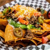 Taco Nachos · Tortilla chips topped with taco meat, queso, Monterrey jack and cheddar cheese, tomato, and ...