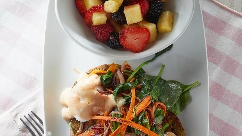 California Veggie Benedict · Grilled vegetarian patties topped with carrot, purple onion and spinach sesame sauté, poached eggs and garlic chili hollandaise. Served with fresh seasonal fruit.