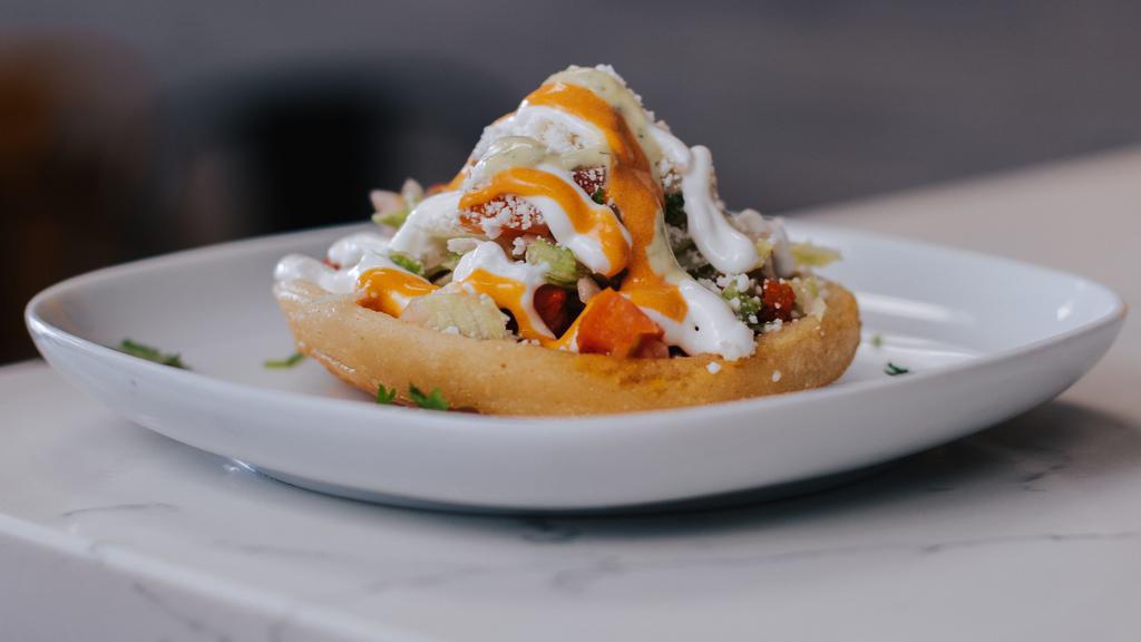 Sopes · Thick corn tortilla with refried beans and your choice of meat topped with sour cream, lettuce, tomato and cheese.