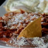 Chilaquiles · Strips of fried corn tortillas submerged in salsa.