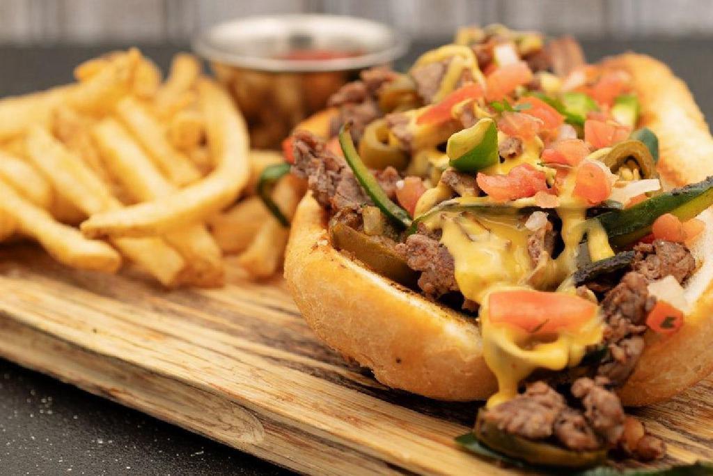Texas-Style Cheesesteak · thin sliced sirloin · queso · peppers · jalapeños · pico de gallo · toasted hoagie roll · served with seasoned French fries