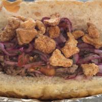 Sanduche De Chancho (Pulled Pork Sandwish) · Pulled pork inside a fresh Cuban bread topped with pork cracklings and pickled onions.