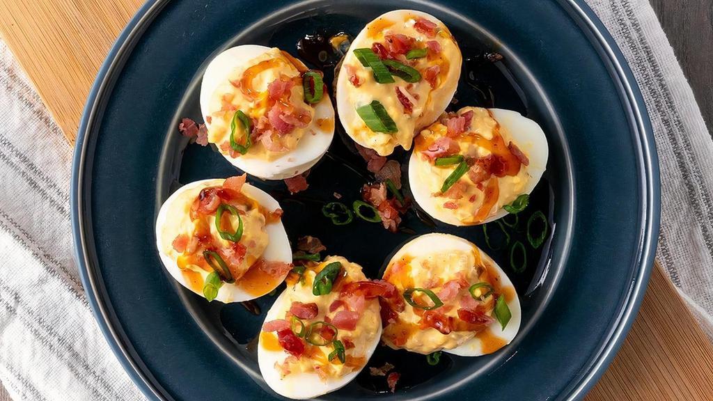 Deviled Eggs · Six classic deviled eggs, topped with bacon & green onions, drizzled with bourbon BBQ sauce and served over coleslaw.