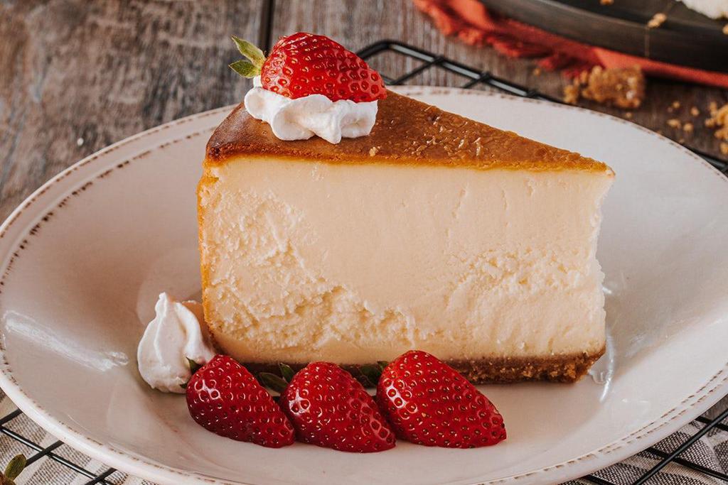 Big Ole  Cheesecake · A towering slice of classic, velvety New York-style cheesecake on a graham cracker crumb crust served with fresh strawberries and whipped cream.