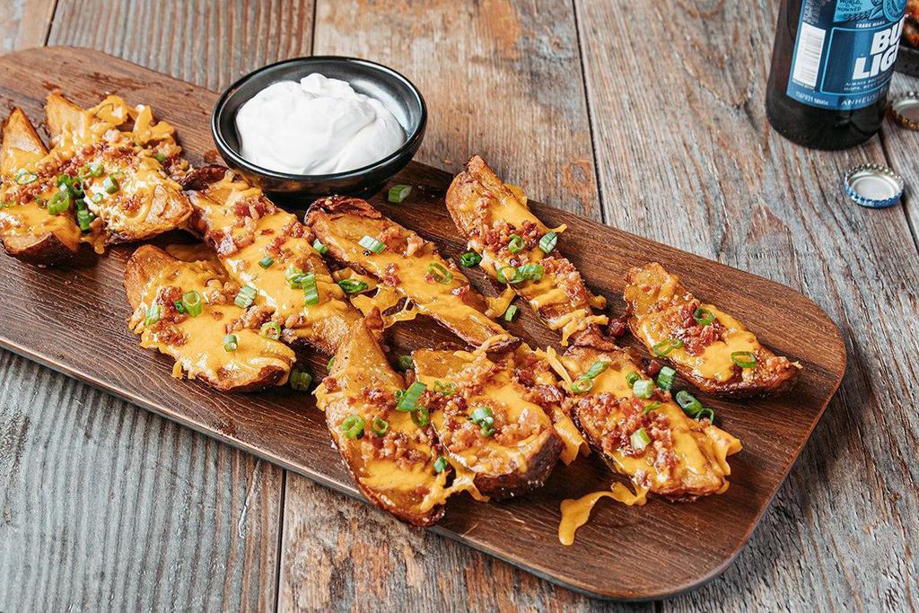 Party Pack Made-From-Scratch Potato Skins · Topped with bacon, shredded cheddar cheese, green onions & served with sour cream.. Serves 10-12.