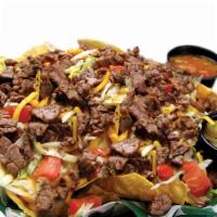 Steak Nachos · Crispy tortilla chips smothered with queso and topped with Cheddar Jack cheese, lettuce, tom...
