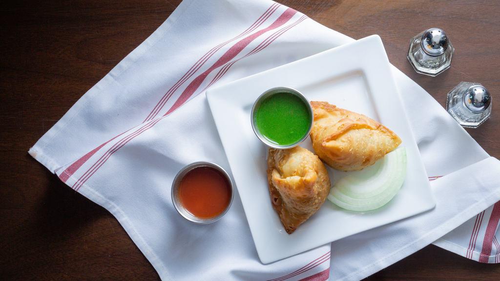 Vegetable Samosas · 2 pieces. Triangular puffed pastry stuffed with cubed potatoes, green peas, carrots, and mildly spiced 'paach-foron'. Served with Tamarind sauce & Mint-Yogurt sauce.