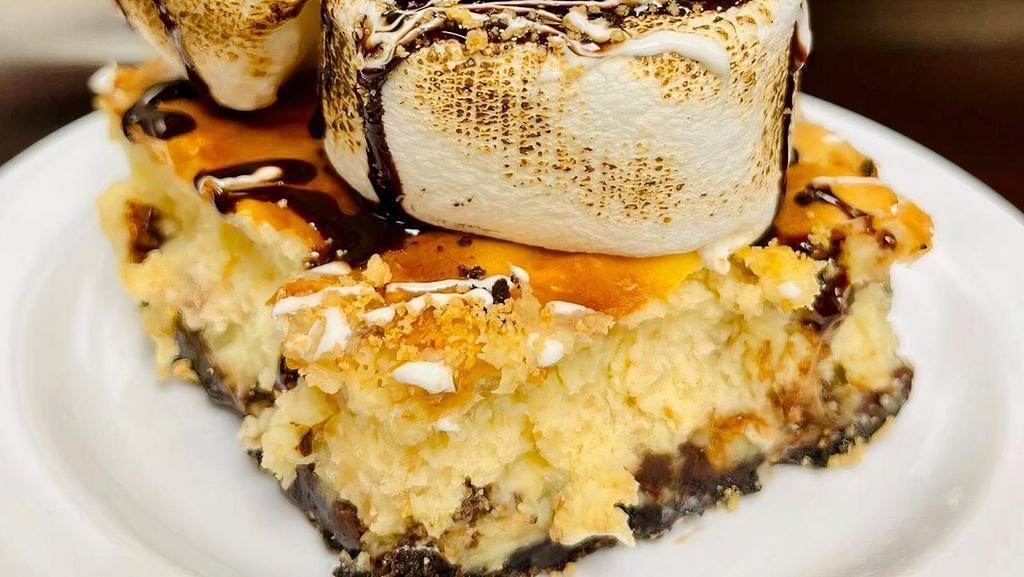 Smore Cheesecake · We have taken our signature cheesecake to the next level with marshmallows, chocolate chips and  graham crackers. Then topped it with a toasted marshmallow and chocolate fudge!