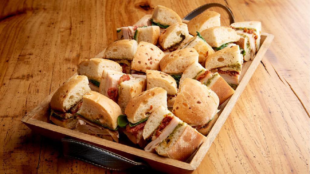 Mini Tuscan Focaccia Tray (2910 Cal)  · Roasted turkey breast, roasted tomatoes, pesto aioli and Asiago mini sandwiches are paired with nitrite-free smoked turkey breast, chipotle aioli, bacon, organic spinach and provolone mini sandwiches, toasted on herb focaccia. (20 Mini Sandwiches)