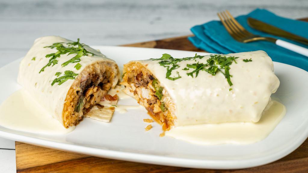 Big Tex Burrito · A flour tortilla rolled and stuffed with skirt steak, chicken, shrimp, bell peppers, tomatoes, onions, rice, sour cream. Topped with cheese dip and cilantro.