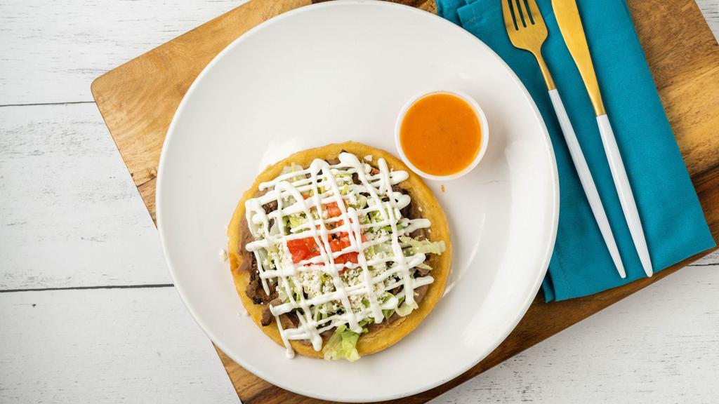 Sope · A masa corn patty topped with refried beans, lettuce, pico de gallo, sour cream and queso fresco. Grilled chicken - Steak - Pastor - Carnitas.