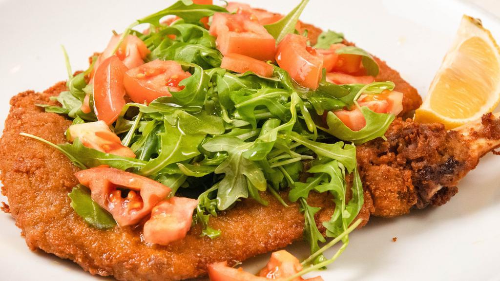 Costata Di Vitello Alla Milanese · Veal chop butterfly Milanese style served with arugula and tomatoes.