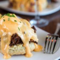 Eggs Cochon · Apple-braised pork debris over a housemade buttermilk biscuit with two poached eggs and holl...