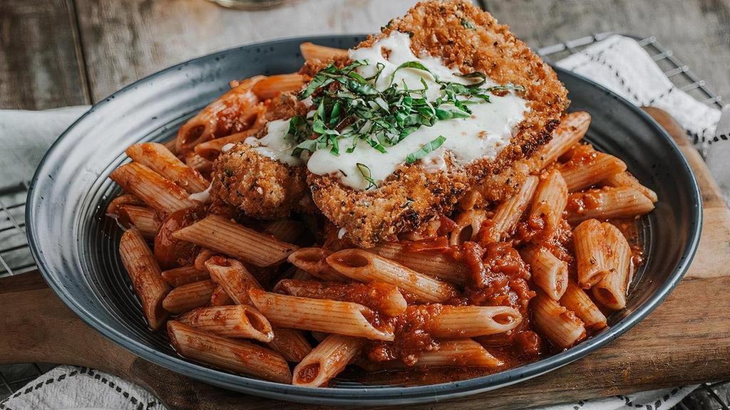 Chicken Parmesan · Basil-parmesan crusted chicken breast, mozzarella, penne, blistered tomatoes, fresh basil & signature red sauce.
