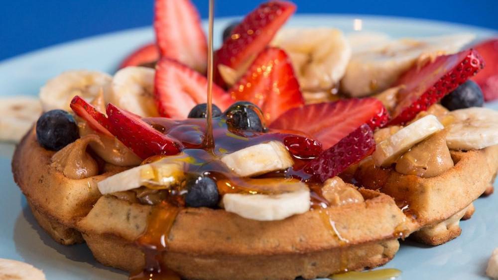 Belgium Chia Waffle · Belgium chia waffle, with bananas, strawberries, blueberries, a side of peanut butter and honey.