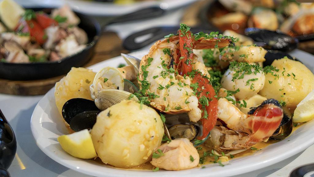 Parrilhada De Mariscos (1 Person) · Grilled Seafood Mix in White Wine and Garlic Sauce with Lobster, Scallops, Shrimp, Clams, Mussels, Squid, Fish, Salmon and steamed Potatoes