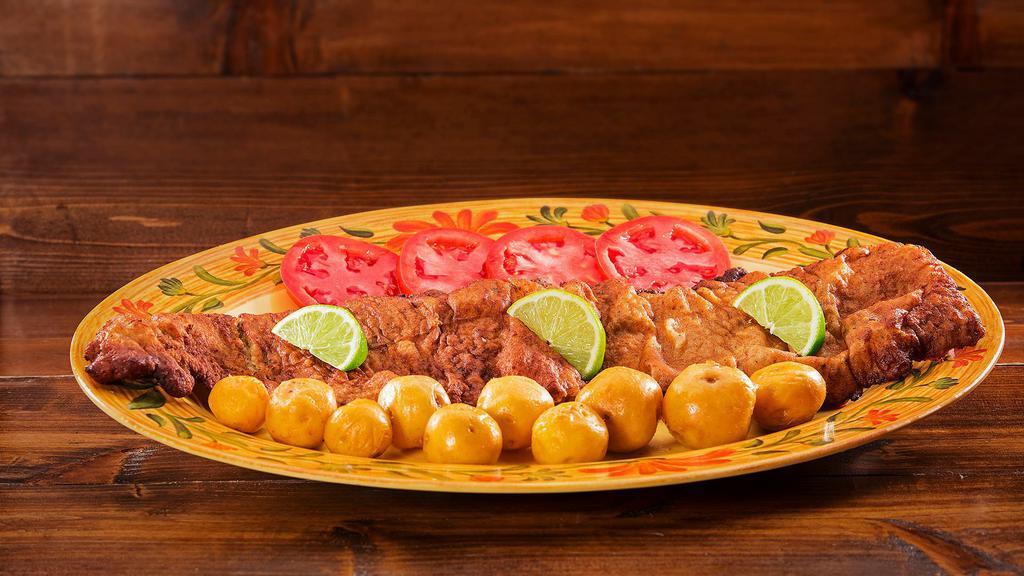 Chuletazo · Fried breaded pork loin, with your choice of one side, one slice of tomato and limes.