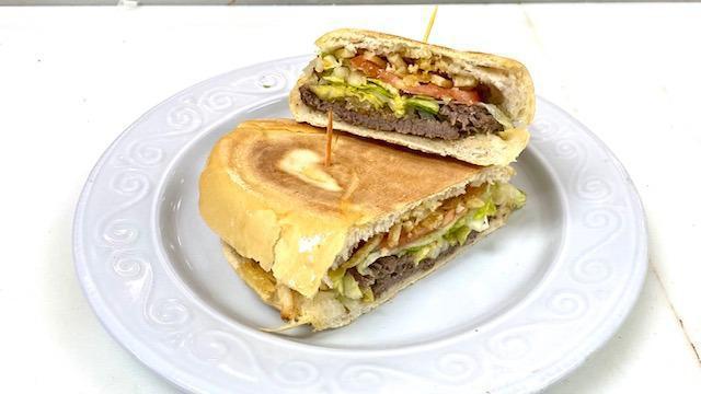 Steak Sandwich / Pan Con Bistec (8459) · Cuban steak grilled with onions, lettuce, tomatoes, shoestring potatoes, mayonnaise on a Cuban bread roll. / Bistec a la plancha con cebollas y mojo, lechuga tomate, papitas fritas, mayonesa en un pan cubano.