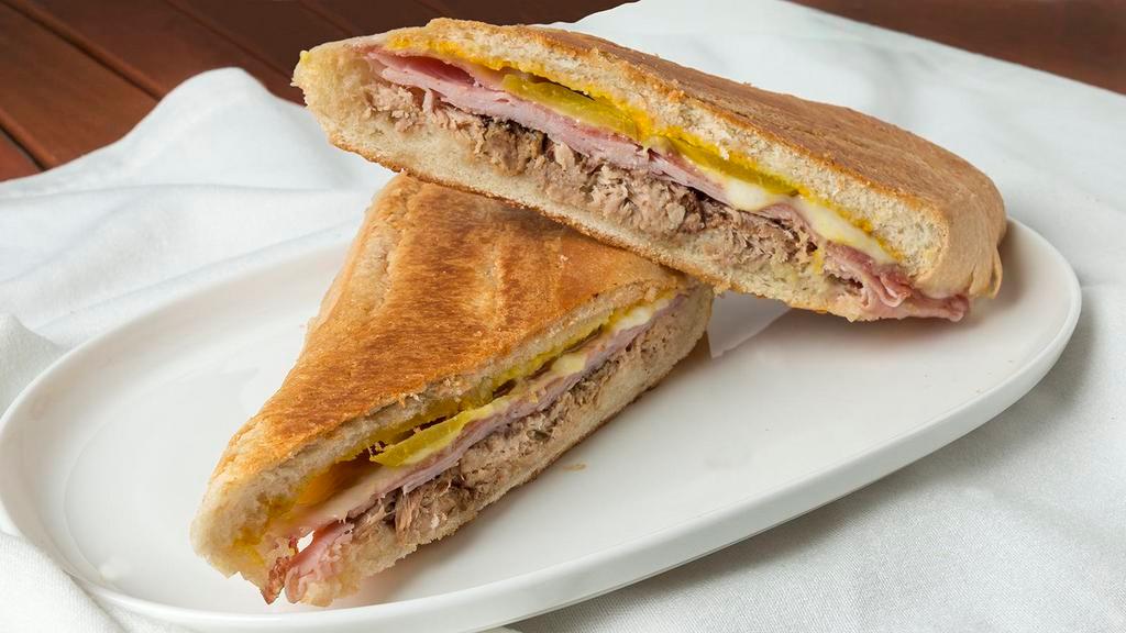 Authentic Cuban Sandwich · Homemade Mojo marinated Pork roasted and pulled, Baked Ham, Genoa Salami, Dill Pickle, Mustard, Swiss Cheese Pressed on Authentic Cuban Bread.