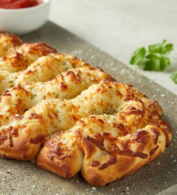 Asiago Cheese Bread (Full) · Fresh baked artisan pull-apart bread topped with Asiago and Romano, served with marinara sauce for dipping. Full size serves 4.