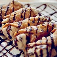 Cannoli · 3 Hand Stuffed Cannoli's dusted in powdered sugar & drizzled with chocolate sauce