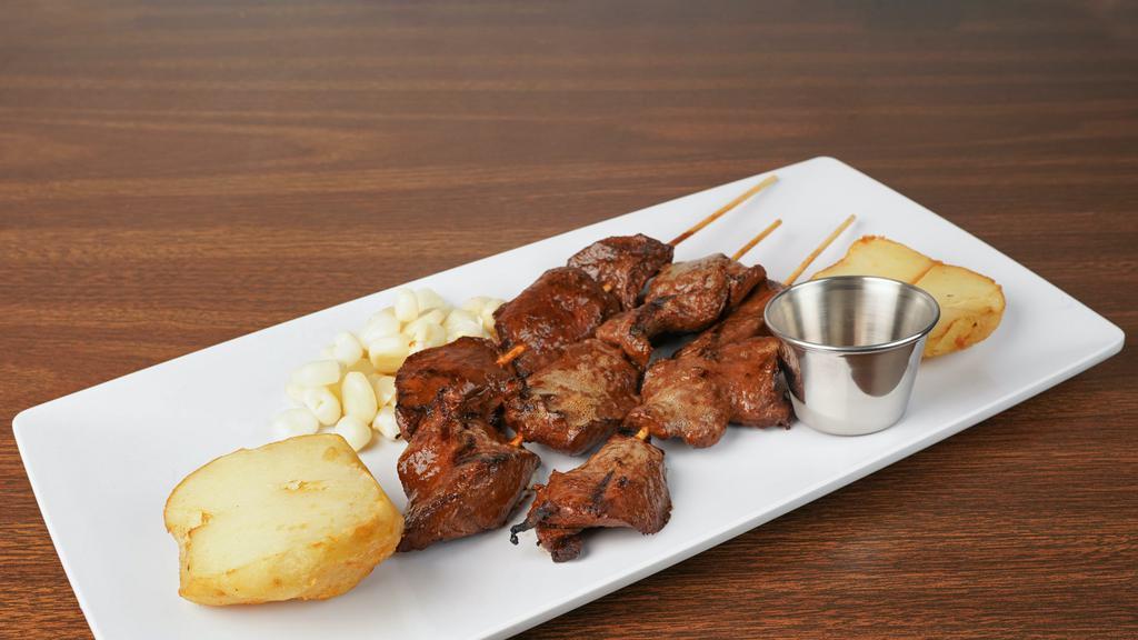 Anticuchos · Beef heart skewers on the grill served with golden potatoes and Peruvian corn.