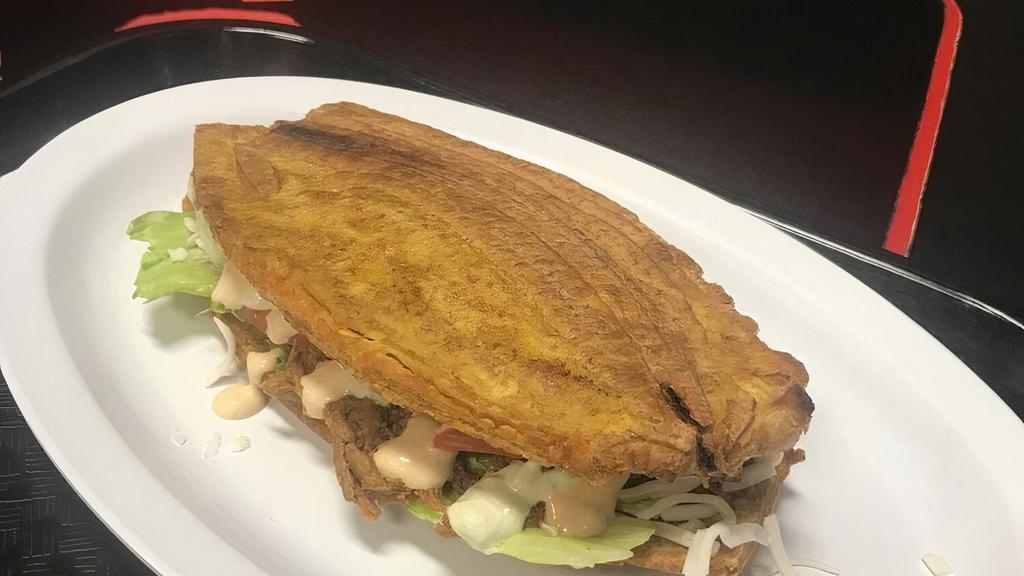 Patacón Mixto · Sandwich of sweet fried plantains filled with grilled beef and chicken (mixed) or with shredded beef and chicken (mixed), mozzarella cheese, avocado, lettuce, tomato, green sauce, pink sauce, and pineapple sauce