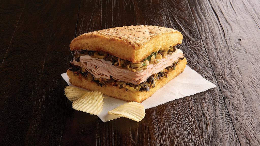 1/4 Roasted Turkey Breast Muffaletta (490 Cal) · A New Orleans original! Grilled, A quarter sandwich with crusty Muffaletta bread spread to the edges with our family-recipe olive mix and provolone is melted over layers of roasted turkey breast. Served with chips or baked chips (150/100 cal) and a pickle (5 cal).