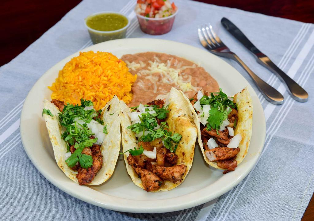 Tacos Al Pastor · Specially marinated pork loin grilled with pineapples and topped with Cilantro and onions. Rice and Beans on the side.