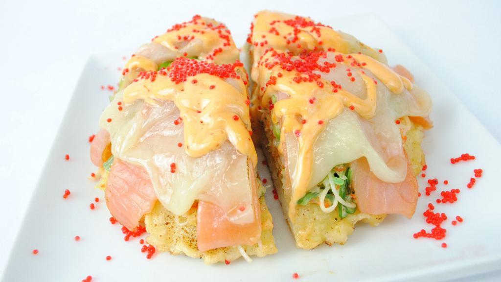 Sushi Pizza · A base of sushi rice tempura, krab, wakame salad, spicy mayo, masago, avocado, red tobiko, tempura flakes with smoked salmon on top and melted provolone cheese.