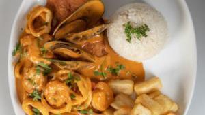 Pescado A Lo Macho · Fried white fish in a creamy seafood sauce served with fried golden yucca, and white rice.