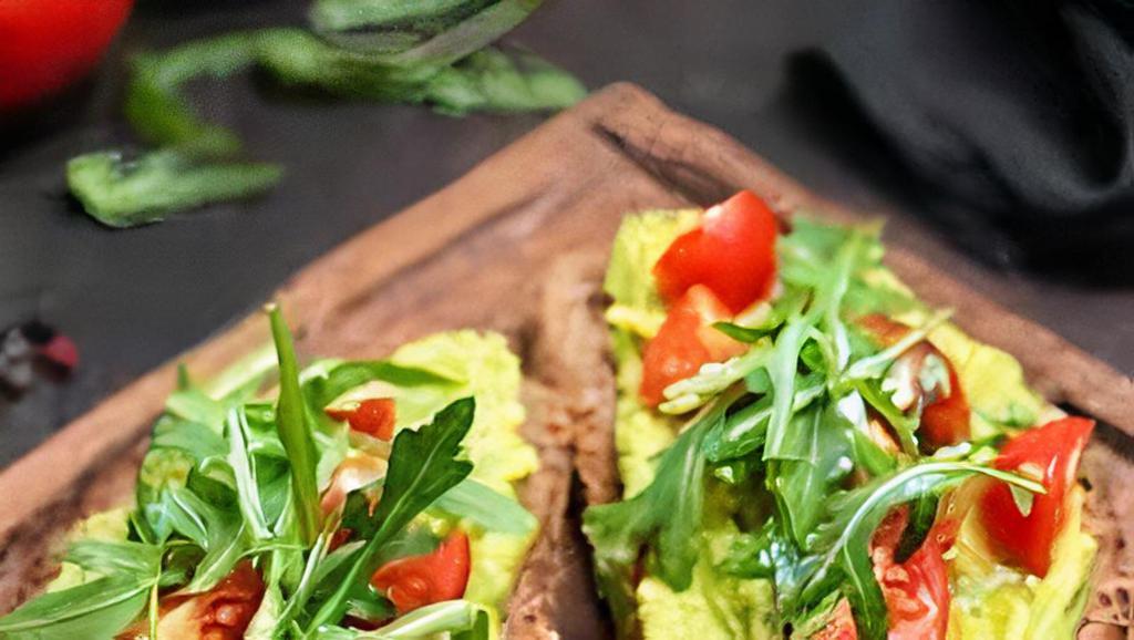 Tostada De Aguacate · Grilled sourdough bread with avocado spread, heirloom tomato and cucumbers. Garnished with fresh herbs.