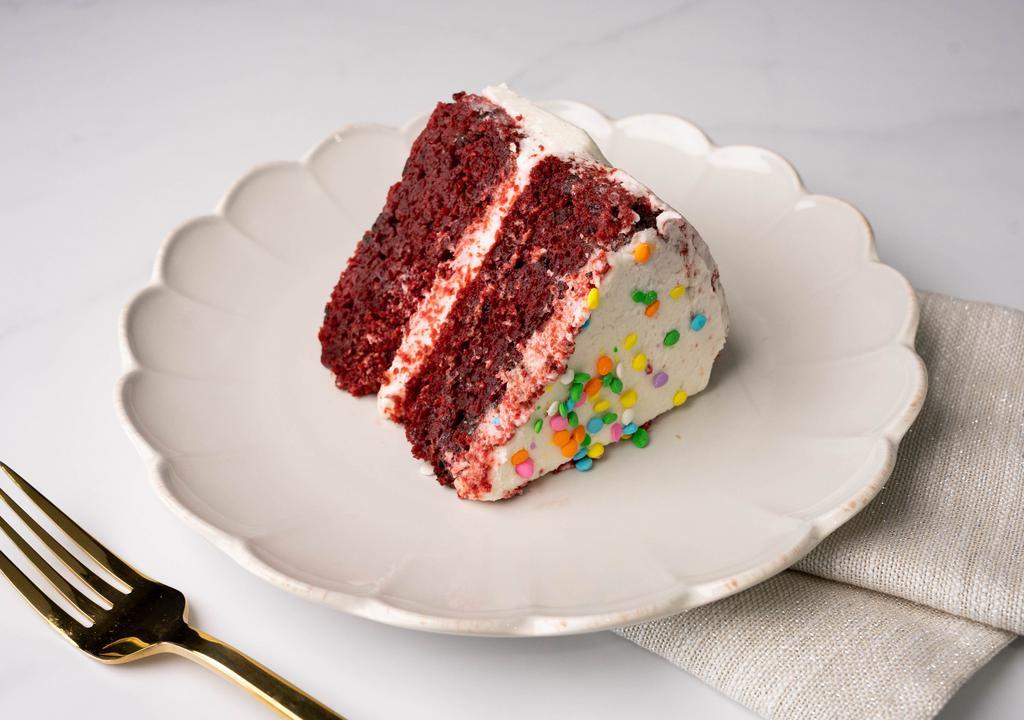 Red Velvet Cake Slice · A slice of our moist red velvet cake with chocolate chips, frosted with vanilla buttercream frosting.