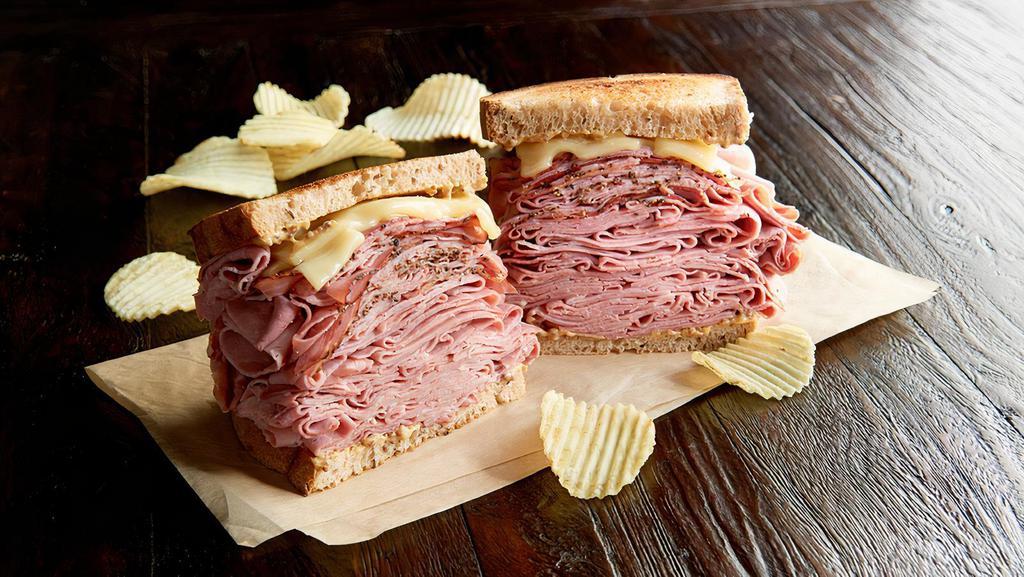 The New York Yankee Regular · 3/4 pound combo of hot corned beef and pastrami, Swiss on toasted marbled rye. Served with chips or baked chips (150/100 cal) and a pickle (5 cal).