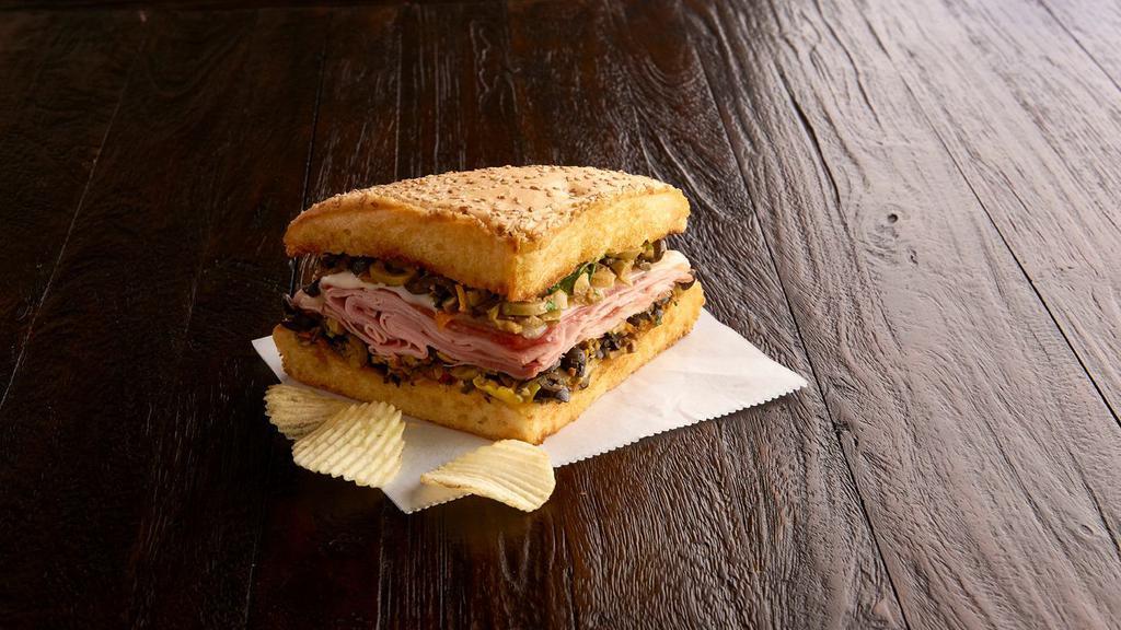 1/4 Ham & Salami Muffaletta (510 Cal) · A New Orleans original! Grilled, crusty Muffaletta bread is spread to the edges with our family-recipe olive mix and provolone is melted over layers of nitrite-free ham and salami. Served with chips or baked chips (150/100 cal) and a pickle (5 cal).