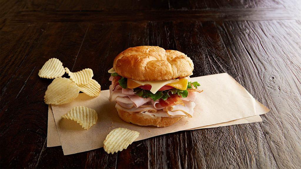 Club Royale Regular · Nitrite-free smoked turkey breast and ham, bacon, Swiss, cheddar, leafy lettuce, tomato, honey mustard, on a toasted croissant. Served with chips or baked chips (150/100 cal) and a pickle (5 cal).
