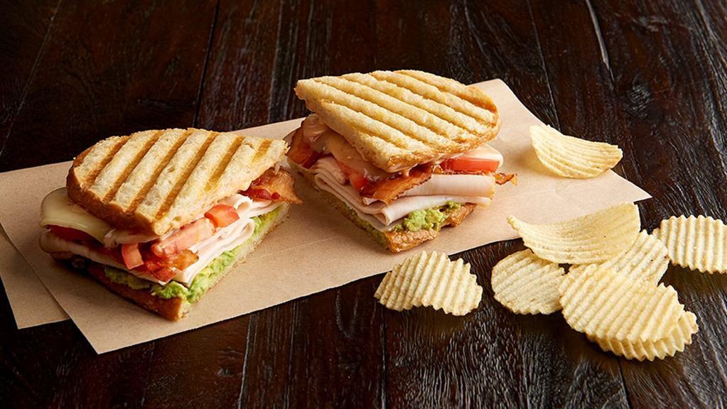 Smokey Jack Panini Regular  · Nitrite-free smoked turkey breast, bacon, jalapeño pepper jack, guacamole, Roma tomatoes, 1000 Island dressing, on sourdough bread. Served with chips or baked chips (100/150 cal) and a pickle (5 cal).
